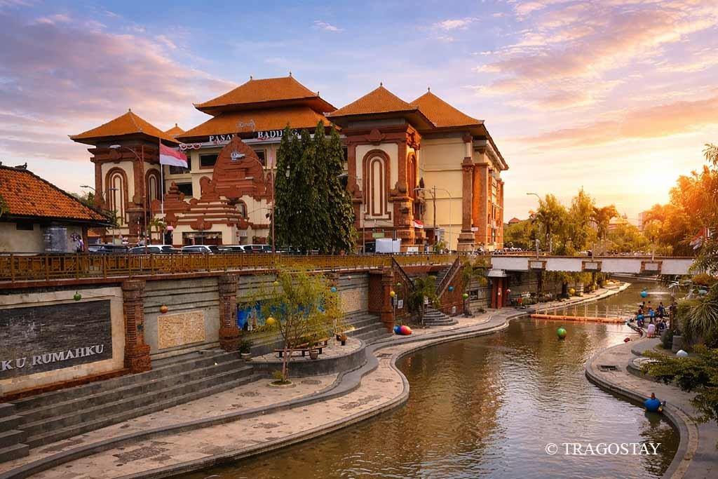 Badung Market building beside the Badung River with a scenic pedestrian bridge.