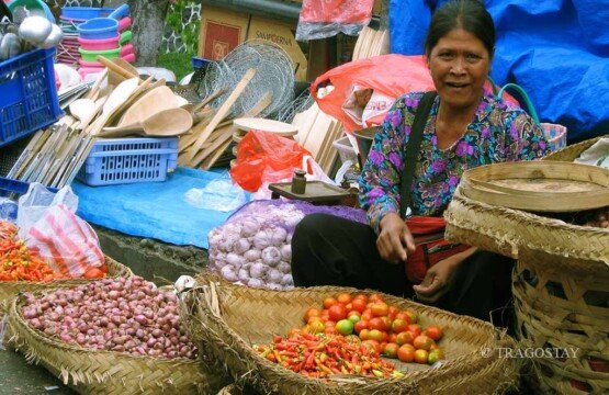 A traditional seller at Badung Market offering Balinese snacks and daily necessities.