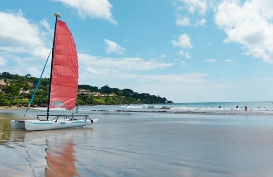 Jimbaran Beach with a traditional sailing boat on the horizon of Bali tourist attractions.