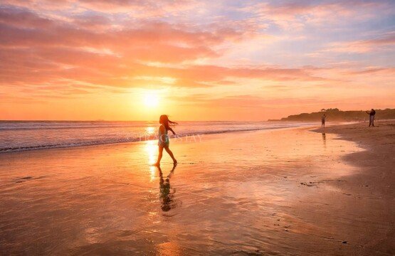 Happy children playing in the soft volcanic sand at Kelating Beach, Bali.
