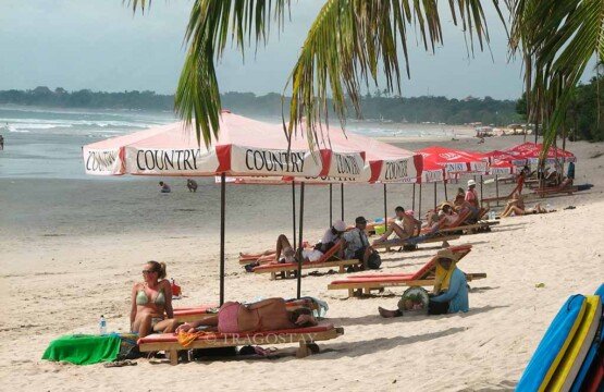 Tourists enjoying relaxation on Kuta Beach Bali Tourist Attractions with bean bags and ocean views.