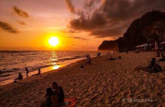 Spectacular Melasti Beach sunset with orange and purple sky over Bali tourist attractions.