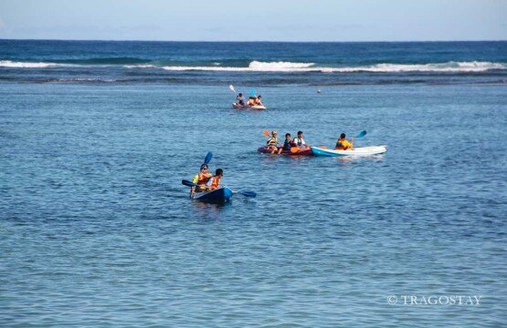 Tourists enjoying a colorful canoe experience at Pandawa Beach Bali on a sunny day.