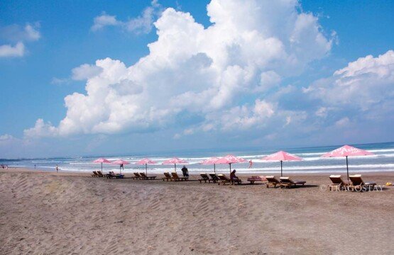 Sunny day view of Seminyak Beach Bali tourist attractions with blue ocean waves.