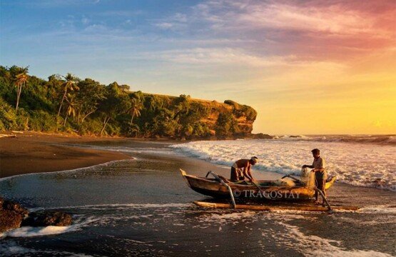 Two local fishermen preparing a traditional outrigger boat on Soka Beach Bali.