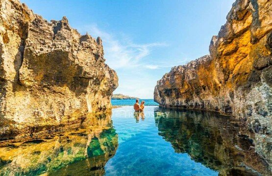 A romantic couple enjoying a swim in the crystal-clear natural pool of Angel's Billabong on a sunny day.