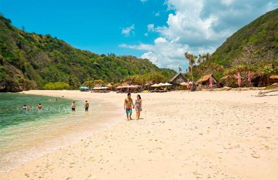 A group of tourists enjoying the vibrant and sunny tropical weather at Atuh Beach in Nusa Penida.