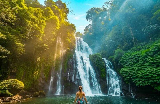 A young woman enjoying a peaceful morning swim in the turquoise waters of the natural pool at Banyumala Waterfall, surrounded by soft light.