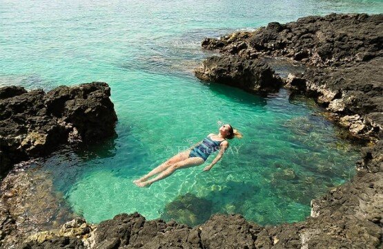 A female tourist swimming in a natural rock pool at Bias Tugel Beach Karangasem.
