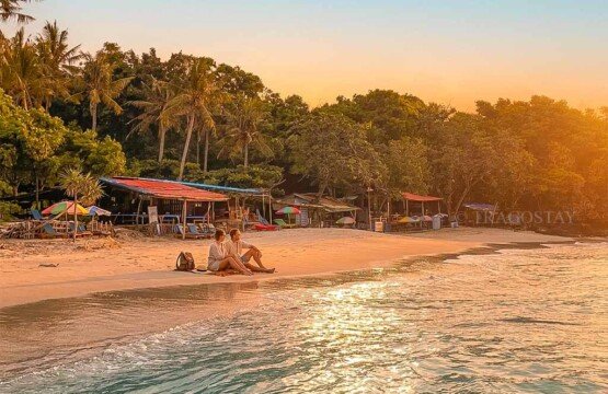 Two tourists sitting on the sand enjoying the golden morning sunrise at Bias Tugel.