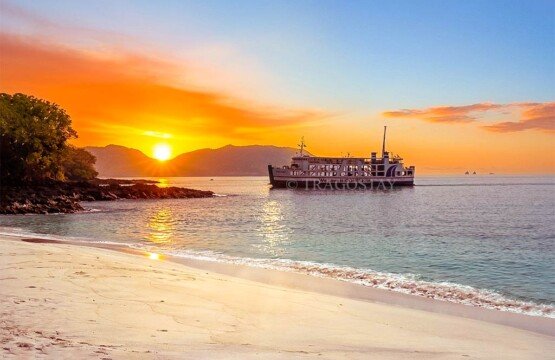 A beautiful sunrise at Bias Tugel Beach with a ferry boat passing in the distance.