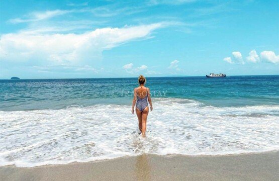 A tourist preparing to swim in the transparent tropical waters of Bias Tugel Beach.