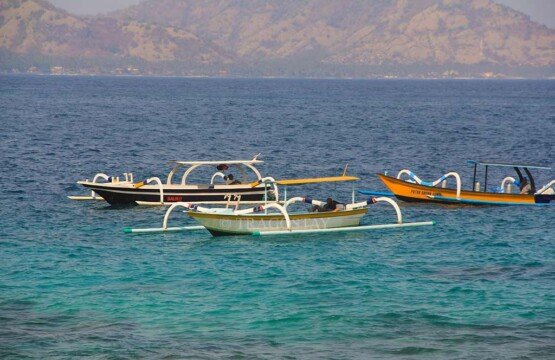 Colorful traditional Balinese jukung boats resting on the white sandy shore of Blue Lagoon Beach Padangbai.
