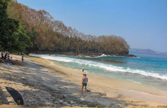 A peaceful scene of travelers relaxing by the clean and transparent ocean water at Blue Lagoon Beach.