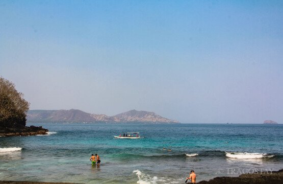 Tourists enjoying a refreshing swimming experience in the clear turquoise waters of Blue Lagoon Beach Padangbai.