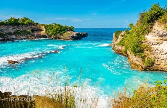 The bright turquoise ocean water inside the rocky bay of Blue Lagoon during a sunny day.