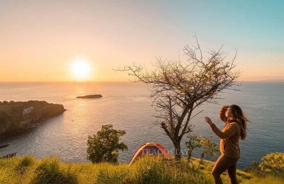 Travelers enjoying a beautiful morning sunrise while camping on the grassy slopes of Bukit Asah.