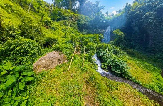 The beautiful white waters of the first main tier of Bunutin Waterfall cascading smoothly down a steep rock wall.