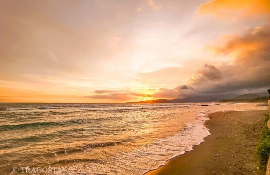 Vibrant sunset colors painting the sky over the horizon of Candidasa Beach in Bali.