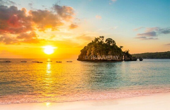 A vibrant and spectacular sunset sky reflecting over the calm waters of Crystal Bay in Nusa Penida.