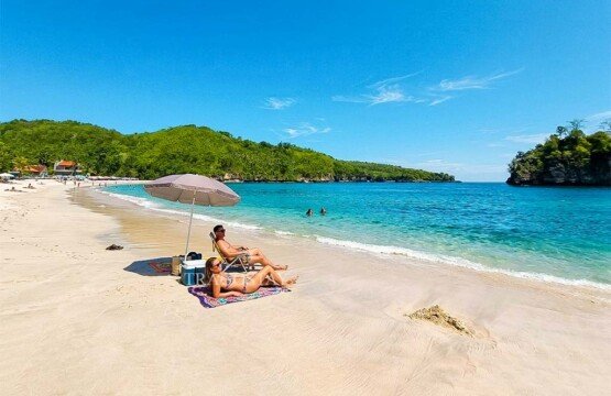 Two international travelers sitting on the sand and relaxing while soaking in the beauty of Crystal Bay.