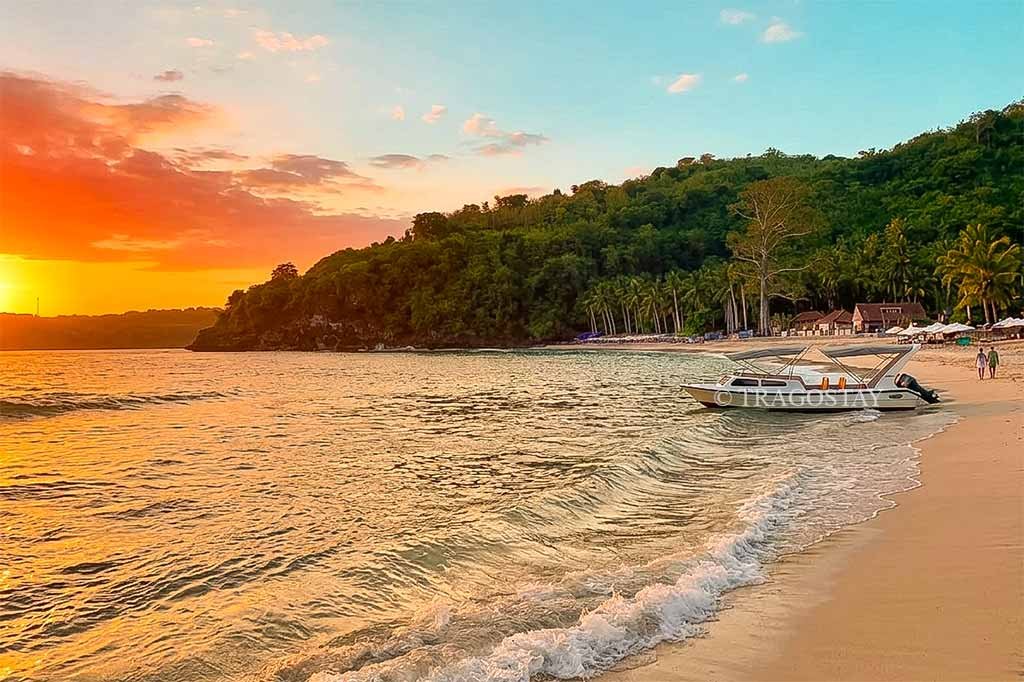 The warm golden glow of the sun setting behind the horizon at Crystal Bay beach.