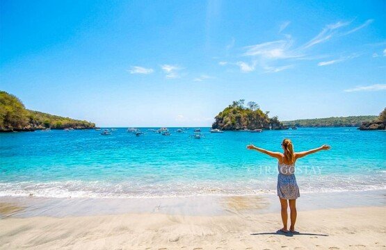 A female traveler posing with open arms while standing on the shoreline of Crystal Bay beach.