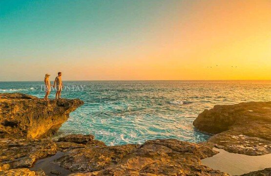 A romantic couple standing on the limestone rocks enjoying a clear and vibrant sunset at Devil’s Tears.