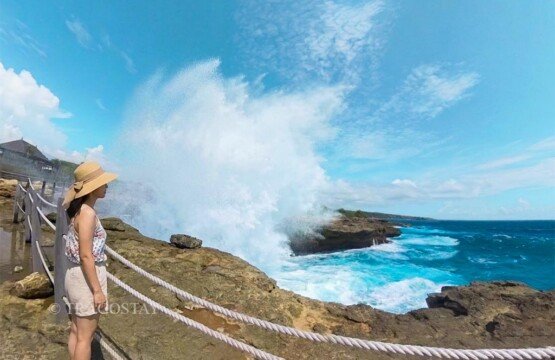 A female traveler standing behind the safety boundary line watching the extreme wave action at Devil’s Tears.