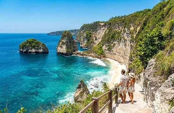 A tourist couple standing on the famous cliffside white stairs of Diamond Beach overlooking the turquoise ocean.