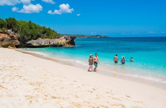 Tourists walking along the shore and enjoying the refreshing ocean waves at Dream Beach.