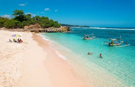 International tourists relaxing on the sand and swimming in the turquoise sea at Dream Beach on a sunny day.
