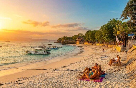 A group of travelers enjoying the spectacular colors of a golden sunset over the horizon at Dream Beach.