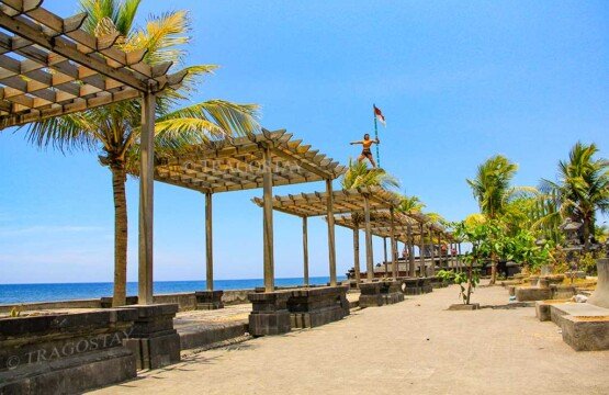 A long row of decorative wooden shade canopies built along the seaside pedestrian promenade leading toward the monument at Ex-Buleleng Harbour.