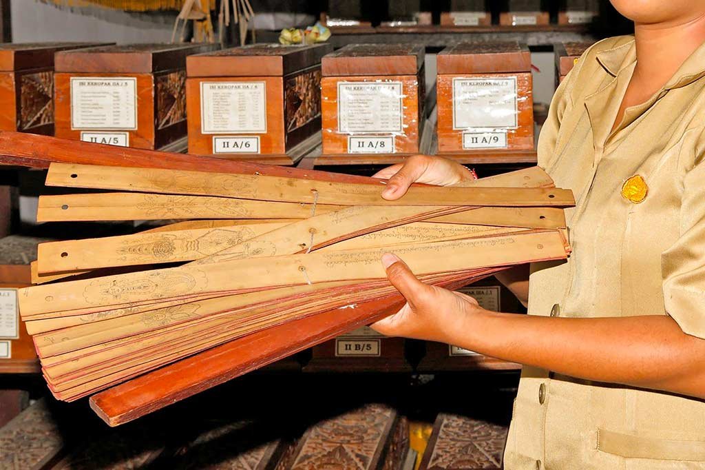 A close-up view of ancient and highly preserved Balinese lontar palm-leaf manuscripts containing historic script text at Gedong Kirtya Museum.