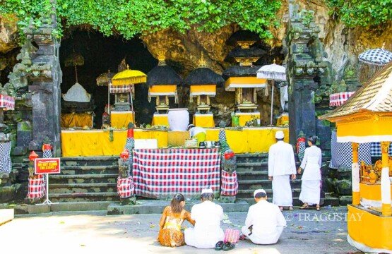 Several Balinese Hindus performing traditional prayers and offerings in the main courtyard of Goa Lawah Temple.
