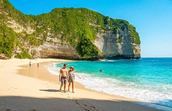 A couple enjoying a peaceful stroll along the pristine white sand at the bottom of Kelingking Beach.