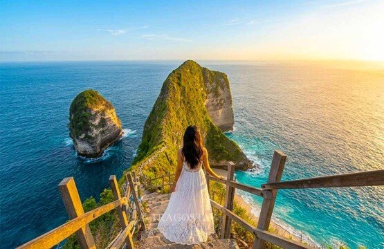 A woman posing while walking down the narrow wooden stairs of Kelingking Beach under a clear afternoon sky.
