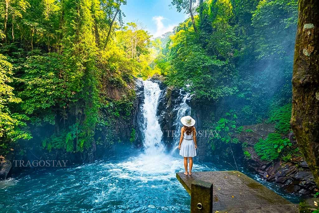 The beautiful, crystal-clear stream of Kroya cascade at Aling-aling Waterfall flowing down a smooth rock incline into a blue plunge pool.