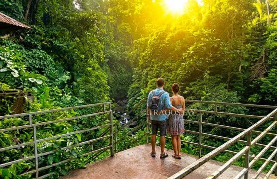 A tourist couple standing on an iron viewing platform overlooking the beautiful river valley at Kuning Waterfall.