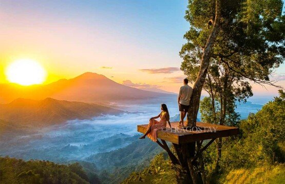 A man leaning against a wooden post and a woman sitting on the platform at Lahangan Sweet during a clear sunset.