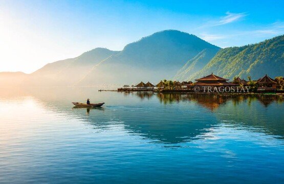 A small traditional fishing canoe drifting quietly on Lake Batur with the steep green Trunyan hills in the background.
