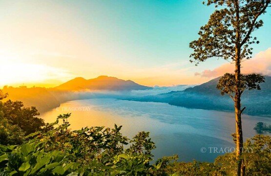 A spectacular sunrise breaking through the clouds, lighting up the entire landscape and water horizon of Lake Buyan.