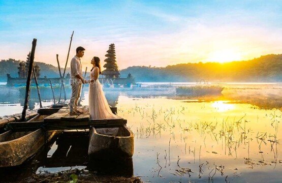 A romantic couple posing together during a magical pre-wedding photo session on a wooden dock over Lake Tamblingan.