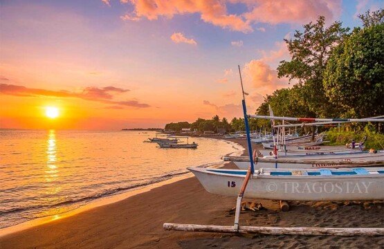 A breathtaking and spectacular sunset casting vibrant orange and purple colors over the calm sea horizon at Lovina Beach.