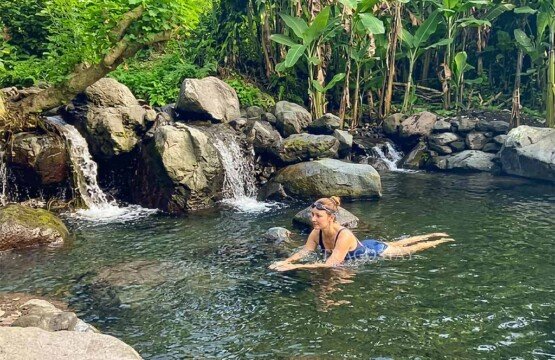 A tourist swimming peacefully in the serene and natural river stone pool at Maha Gangga Valley.
