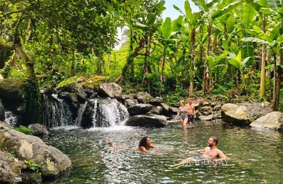 Happy tourists enjoying a refreshing dip in the natural river stone pools at Maha Gangga Valley.