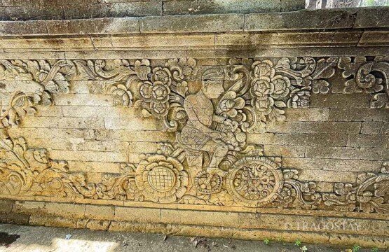 The famous and unique historical stone relief carving of a Dutch man riding a bicycle with floral wheels at Meduwe Karang Temple.