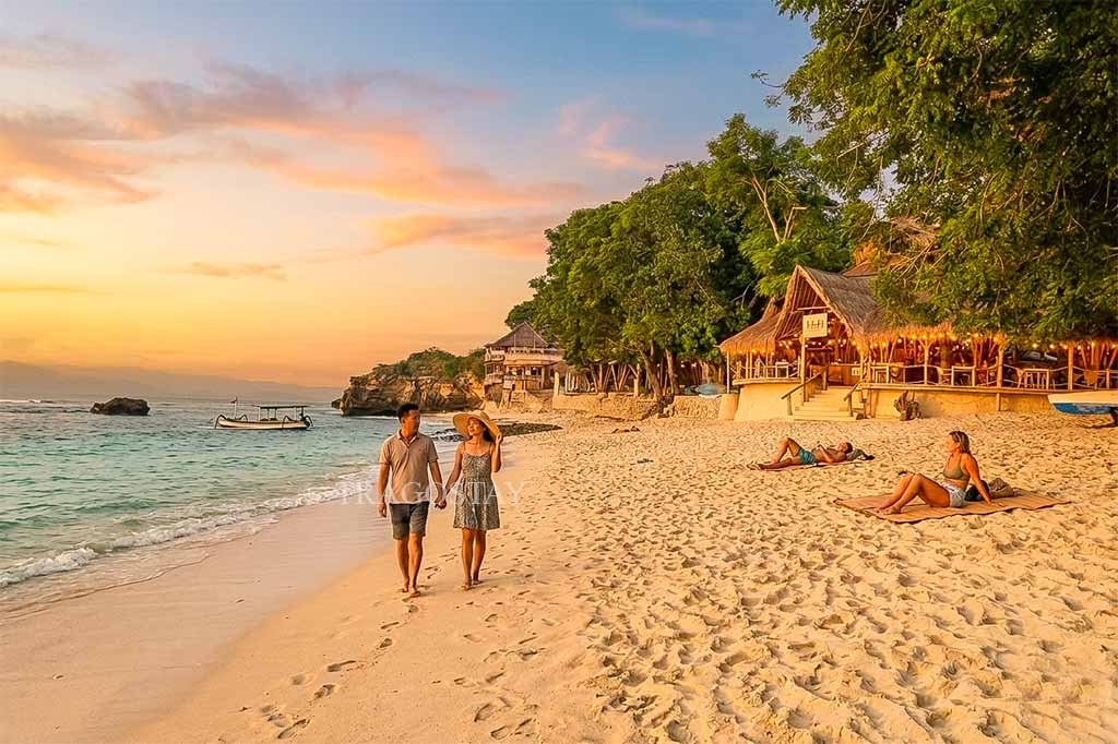 Two travelers enjoying a scenic walk along the shoreline of Mushroom Bay during a clear afternoon.