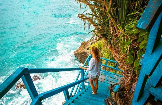 A female traveler standing on the iron staircase looking out at the endless horizon of the Indian Ocean.